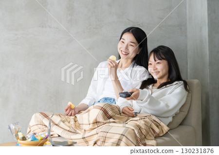 Mother and daughter smiling together on the sofa Mother and daughter smiling together on the sofa 130231876