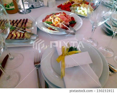 Festive Dining Table Layout Featuring Delicious Food and Guest Card for Special Occasion Festive Dining Table Layout Featuring Delicious Food and Guest Card for Special Occasion 130231911