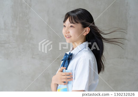 A female student smiling cheerfully while holding study materials 130232026