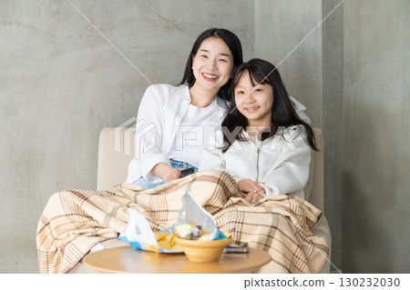 Parents and children wrapped in a blanket enjoying TV Parents and children wrapped in a blanket enjoying TV 130232030