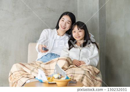 Parents and children wrapped in a blanket enjoying TV 130232031