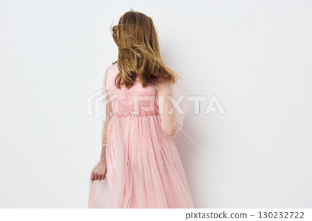 A graceful young girl wearing a pink tulle dress, with flowing hair, facing away on a minimalist white background, embodying innocence and joy A graceful young girl wearing a pink tulle dress, with flowing hair, facing away on a minimalist white background, embodying innocence and joy 130232722