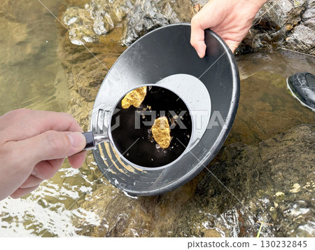 Panning for gold: Close-up of the collected gold dust with a magnifying glass 130232845