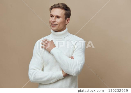 Smiling young man wearing white turtleneck sweater looking away isolated on beige background studio portrait. People lifestyle concept 130232929
