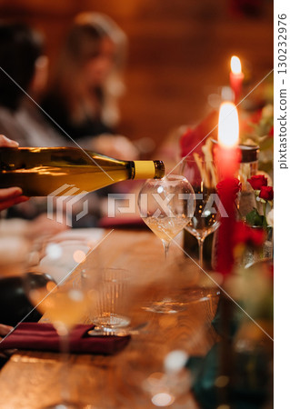 Close-up of white wine being poured into a glass at elegant candlelit dinner celebration Close-up of white wine being poured into a glass at elegant candlelit dinner celebration 130232976