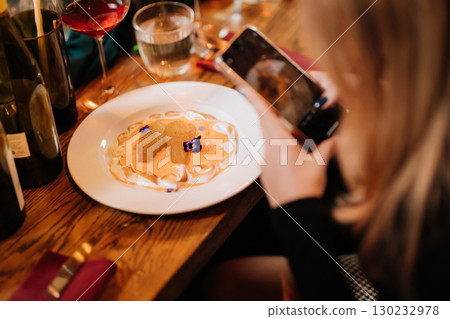 Elegant wine and dessert dinner with guests capturing the moment on phone Elegant wine and dessert dinner with guests capturing the moment on phone 130232978