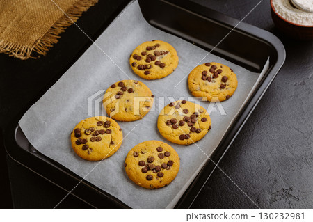Freshly baked chocolate chip cookies on a baking tray with parchment paper Freshly baked chocolate chip cookies on a baking tray with parchment paper 130232981