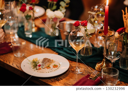 Gourmet fish fillet served with creamy sauce and microgreens on elegant dinner table 130232996