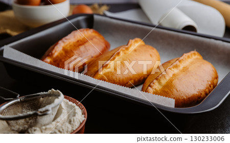 Freshly baked pies in baking tray, traditional homemade pastry with golden crust. Ukrainian piroshki 130233006