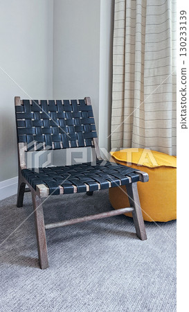 Stylish woven chair with a modern design placed next to a vibrant yellow pouf in a cozy interior setting showcasing contemporary decor Stylish woven chair with a modern design placed next to a vibrant yellow pouf in a cozy interior setting showcasing contemporary decor 130233139