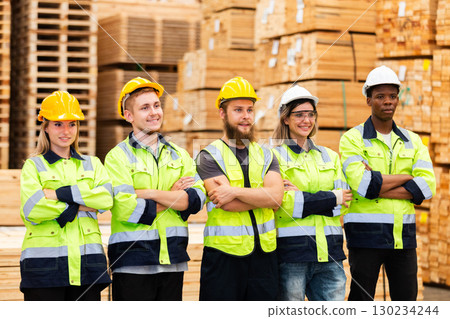 Confident warehouse workers in high visibility safety gear with crossed arms, standing in lumber storage facility, representing unity, professionalism, and industrial team motivation. Confident warehouse workers in high visibility safety gear with crossed arms, standing in lumber storage facility, representing unity, professionalism, and industrial team motivation. 130234244