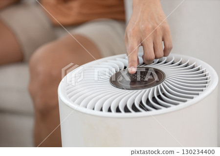 Close up of hand pressing power button air purifier for clean air in house for good health. 130234400