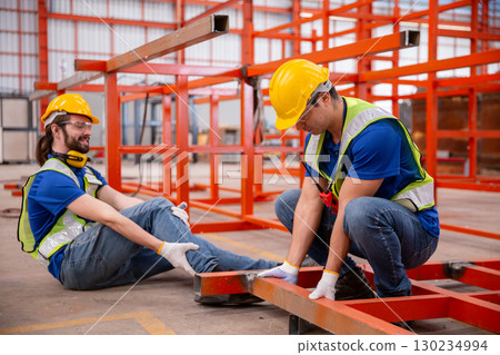 Factory worker injured during accident being assisted by colleague, representing workplace safety, industrial injury, emergency response, teamwork in hazardous environment, and safety training Factory worker injured during accident being assisted by colleague, representing workplace safety, industrial injury, emergency response, teamwork in hazardous environment, and safety training 130234994