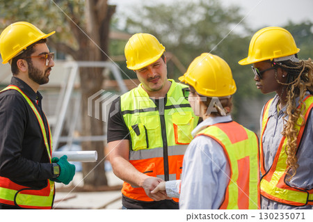 Diverse construction team wearing safety helmets and reflective vests shaking hands at building site symbolizing teamwork, agreement, partnership and successful project collaboration. Diverse construction team wearing safety helmets and reflective vests shaking hands at building site symbolizing teamwork, agreement, partnership and successful project collaboration. 130235071