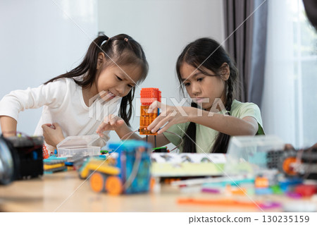 Two asian girls work together on a colorful STEM robotics project, focusing on assembling parts to develop creativity, engineering skills, and problem-solving through hands-on learning. Two asian girls work together on a colorful STEM robotics project, focusing on assembling parts to develop creativity, engineering skills, and problem-solving through hands-on learning. 130235159