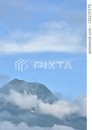 A mountain peeking out from between the clouds A mountain peeking out from between the clouds 130235579