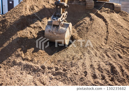 An excavator is actively handling gravel at a bustling construction site with efficiency An excavator is actively handling gravel at a bustling construction site with efficiency 130235682