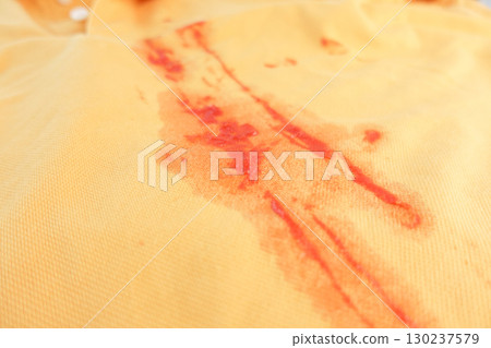 Red stain on yellow fabric from food spill during lunch 130237579