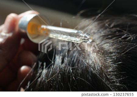 Applying serum to enhance hair health in natural light 130237655