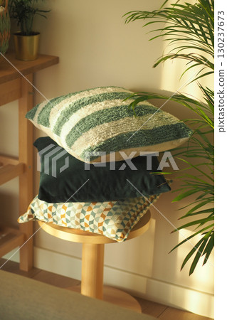 Decorative cushions stacked on a wooden stool in sunlight Decorative cushions stacked on a wooden stool in sunlight 130237673