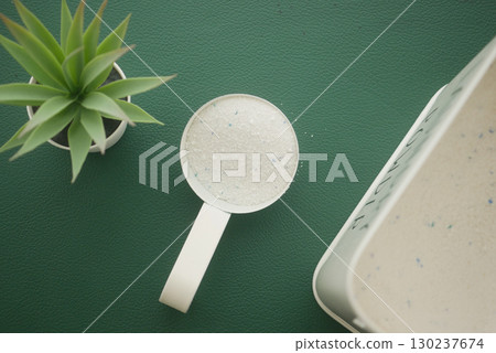 Measuring laundry detergent beside a green tabletop plant Measuring laundry detergent beside a green tabletop plant 130237674