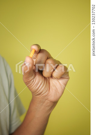 Holding a small yellow object against a bright background 130237702