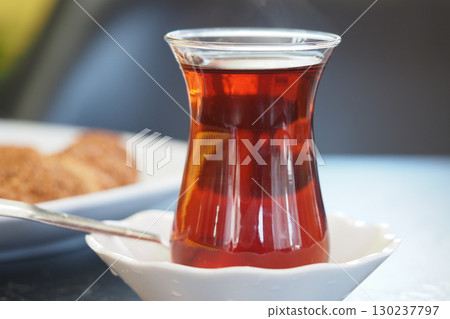 Steaming cup of turkish tea with cookies on a table Steaming cup of turkish tea with cookies on a table 130237797