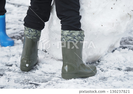 Kids enjoy winter activities while wearing colorful boots 130237821