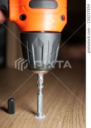 Using a drill to fasten a screw in wood 130237854