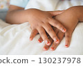 Hands of a child resting on a white blanket 130237978