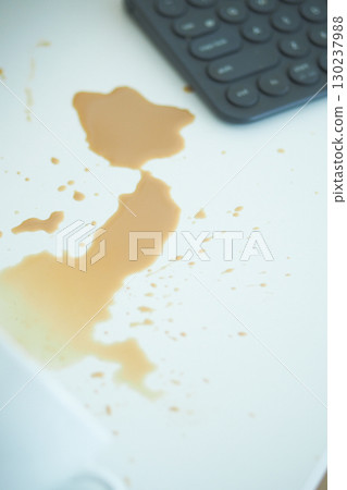 Coffee spill on a white surface near a calculator Coffee spill on a white surface near a calculator 130237988