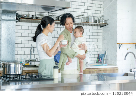 Mom cooking in the kitchen and dad taking care of the kids 130238044