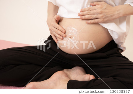 Woman applying cream to her enlarged belly 130238557