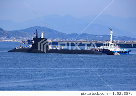 A submarine and tugboat arriving in port 130238873