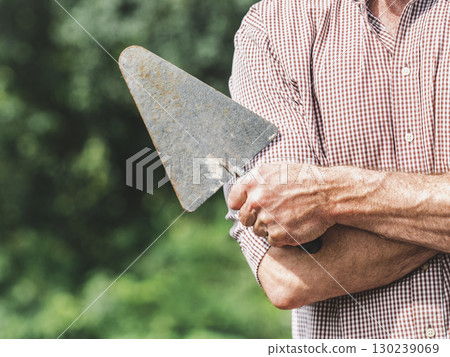 Attractive builder, masonry trowel and red shirt 130239069