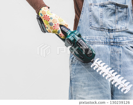 Cute woman, work clothes and hedge trimmer. Studio shot. 130239126