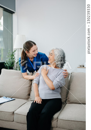 Young nurse helping elderly woman walk in the room, holding his hand, supporting. Treatment and rehabilitation after injury 130239330