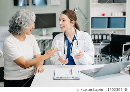 Doctor discussing treatment with male patient talking and laughing sitting on examination bed in clinic or hospital 130239346