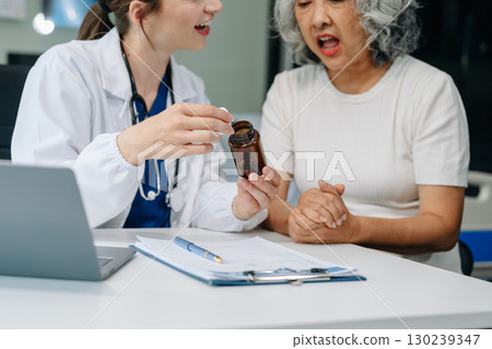Doctor discussing treatment with male patient talking and laughing sitting on examination bed in clinic or hospital 130239347