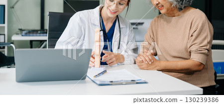 Doctor in white suit take notes while discussing and Asian elderly, man patient who lying on bed with receiving saline solution 130239386