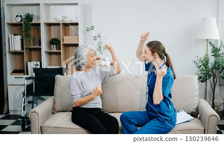 Young nurse helping elderly woman walk in the room, holding his hand, supporting. Treatment and rehabilitation after injury 130239646