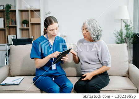 Young nurse helping elderly woman walk in the room, holding his hand, supporting. Treatment and rehabilitation after injury 130239650