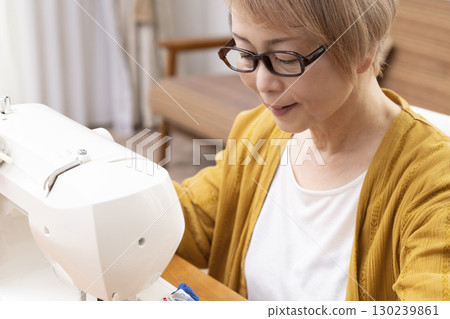 A senior woman happily sewing clothes and accessories with a sewing machine 130239861