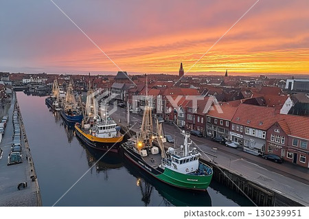 Fiery Sunset Over Harbor Town with Docked Fishing Vessels 130239951