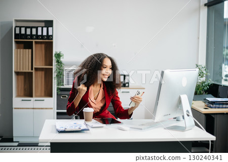 Confident female entrepreneur looking at the camera while standing. Young businesswoman standing Confident female entrepreneur looking at the camera while standing. Young businesswoman standing 130240341