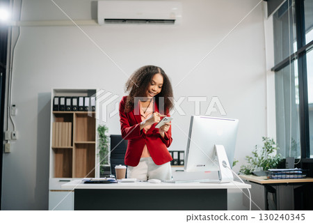 Confident female entrepreneur looking at the camera while standing. Young businesswoman standing 130240345
