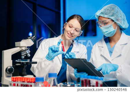 Modern Medical Research Laboratory Portrait of Two Scientists Working, Using Digital Tablet, Analyzing Samples, Talking. 130240546