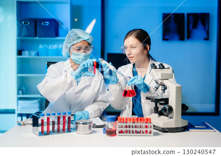 Modern Medical Research Laboratory Portrait of Two Scientists Working, Using Digital Tablet, Analyzing Samples, Talking. 130240547