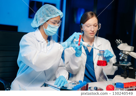 Modern Medical Research Laboratory Portrait of Two Scientists Working, Using Digital Tablet, Analyzing Samples, Talking. Modern Medical Research Laboratory Portrait of Two Scientists Working, Using Digital Tablet, Analyzing Samples, Talking. 130240549