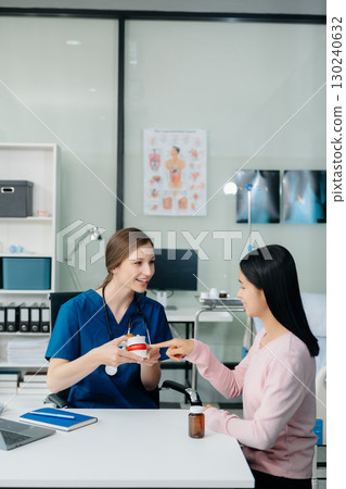 Doctor discussing treatment with Female patient talks to discuss results or symptoms and sitting on examination desk 130240632